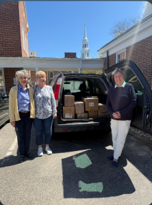 Three women loading up a van with boxes of donated goods.